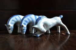 Porcelain horse and zebra figurines. Blue and white vintage figurine miniatures on a dark background.