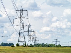 Electricity pylons going into the distance over summertime countryside