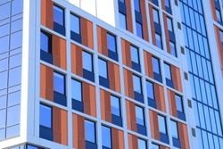 Close up of orange and red cladding around windows of a block of student accommodation in an English city. 