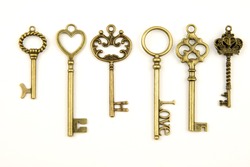 Ornamental medieval vintage keys with intricate forging, composed of fleur-de-lis elements, victorian leaf scrolls and heart shaped swirls. antique golden door key isolated on white background