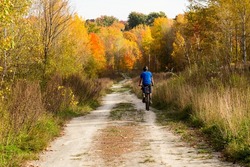 Back view of man cycling on dirt road seen during a beautiful fall afternoon, Cap-Rouge area, Quebec City, Quebec, Canada