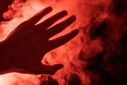 Hand on the background of red steam. Concept - the harm of smoking, electronic cigarettes, fire
