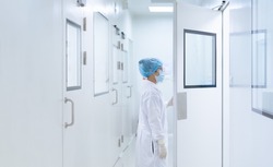 Unidentified microbiologist is open the cleanroom door to enter the room in clean area of microbial laboratory in pharmaceutical factory, concept of science, healthcare and safety operation.