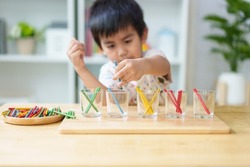 Blurred of asian 3 years old boy is learning to sorting the color rod to the glass, concept of homeschool, montessori, freedom, education, activity for child development and sensory activity for kid.