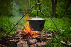 Hiking pot, Bowler in the bonfire. Fish soup boils in cauldron at the stake. Traveling, tourism, picnic cooking, cooking at the stake in a cauldron, fire and smoke.