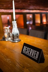 A modern idea for a reserved table with the inscription Reservation of your place. Idea restaurants the inscription reserved on a wooden table in a cafe.
