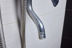 A thin stream of hard water flows from an old tap aerator. Old Bathroom Sink Faucet contaminated with calcium and grime.