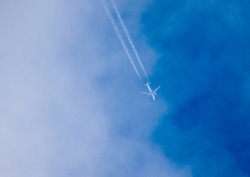Passenger plane in flight, at high altitude, among the clouds. Contrail.
