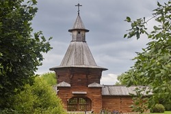 Beautiful wooden fortress made of logs, tower with entrance wolves on the background of the summer landscape and gray sky. Traditional old architecture of the north of the Middle Ages.