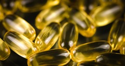 Fish Oil Omega 3 golden capsules on black blackground
