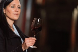 Woman tasting wine at the wine cellar with barrels in background