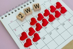 2WW word on wooden block with red heart shape on calendar. Surviving the Two Week Wait when you're trying to conceive.