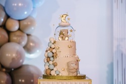 Cake on a background blue, gold, brown balloons for birthday party. Baby shower. Trendy Cake with a figure bear for boy. Celebration baptism concept. Delicious reception. Photo wall, arch with decor.
