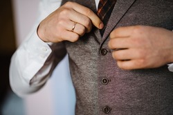 Man fastens the buttons. The groom in a suit. Close up. Man is buttoning his vest. Perfect to the last detail. Modern businessman. Fashion shot of a handsome young man in elegant classic suit.