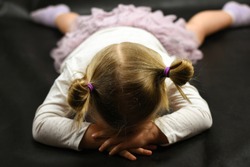 Child girl upset lying on the floor and crying on a black background