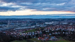 Germany, Beautiful aerial view above industry, arena, highway and houses of stuttgart city with red sky after sunset in winter season
