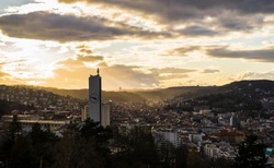 Germany, Stuttgart, Warm orange sunset sunlight and sunbeams shining on skyline of houses of stuttgart city from above