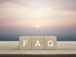 FAQ letter on block cubes on wooden table over city tower and skyscraper at sunset, vintage style, Frequently asked questions, Business customer service and support concept