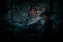Halloween witch holding magic wand standing over dead tree, crow, birds, full moon and spooky cloudy sky, Halloween mystery concept