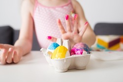 girl paints Easter eggs at home against background of bright decor. kids craft. create art for children