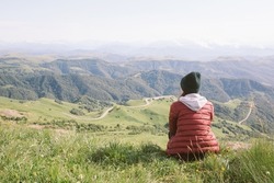 woman is sitting against background of mountains . travel, hiking, journey, outdoor recreation.