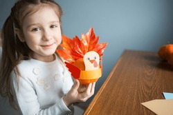 paper craft for kids. DIY Turkey made from pumpkin for thanksgiving day. create art for children. girl playing with toy.