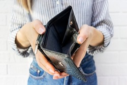Close-up of a young womans hand holding an empty purse. No money in the wallet. Bankruptcy, financial and debt problems, crisis, unemployment, lack of funds to pay expenses and loan credit card.
