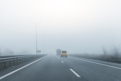 Driver POV on almost empty blue foggy misty rainy highway intercity road with low poor visibility on cold spring autumn morning. Seasonal bad rainy weather accident danger warning. car fog light