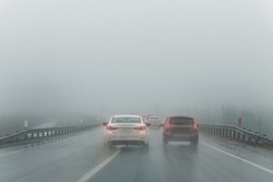 Car overtake rules violation crossing double lane. traffic on foggy misty rainy highway intercity road low poor visibility cold winter autumn day. Seasonal bad rainy weather accident danger warning