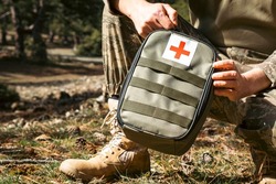 Military army first aid kit. Camouflaged soldier medic. White and red first aid sign.