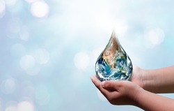 World water day. A globe in the shape of a drop of water falling onto the boy's hand on blue sea background. Elements of this image furnished by NASA 