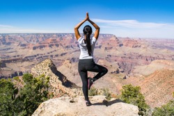 Young Woman Performing One-Legged Yoga Position on Rocky Ledge in front of the Grand Canyon - Grand Canyon National Park, Arizona, USA 