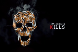 Skull from cigarettes, butts, on a black background. The inscription smoking kills. Creative background. The concept of smoking kills, nicatine poisons, cancer from smoking, stop smoking. Copy space.