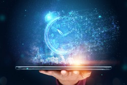 Time management concept, Hand close-up and a tablet with a hologram clock dissolving into air. Time is fleeting, dead line, the passage of time. Copy space