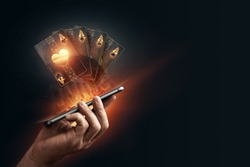 In the hands of a smartphone with playing cards, black-gold background. Concept of online gambling, online casino. Copy space
