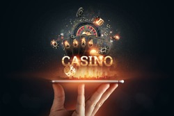 In a man's hand a smartphone with playing cards roulette and chips, black-gold background. Concept of online gambling, online casino. Copy space.