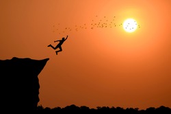 Silhouette of man flying over cliff on sunset background , business concept