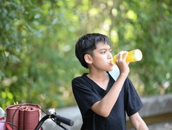 Teenager boy drinking fruit juice in the park camping summer time
