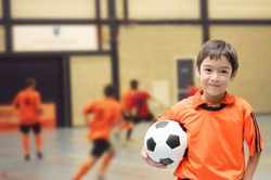Little boy holding football soccer ball indoor gym