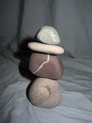 Balancing Wishing Stones with Gravity Only. Wishing Stones. Stones with Lines Through Them. White line through pinkish grey rock. smooth rock. Stone Isolated on Grey Cotton Knit Background. balanced. 
