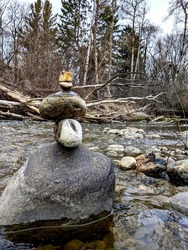 Balancing Stones with Gravity During a walk through the forest. Wild. Meditation. rocks in the running water of stream. only gravity. calming. birch evergreen trees in background. zen. natural calm