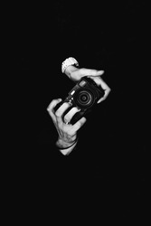 A man photographer holding a camera. Retro camera on a black background.