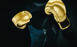 Boxer in gold boxing gloves on a dark black background. Concept of sport and active leisure. Practicing martial arts. Playing sports, taking care of figure, fight and self-defense.