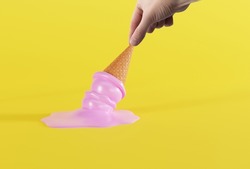 Hand holds melted ice in a waffle on the ground and yellow background. The concept of eating ice cream, cooling down. 