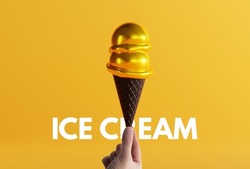 Hand holds gold ice cream in a black waffle on the ground and yellow background. The concept of eating ice cream, cooling down. Modern ice cream with a black waffle.