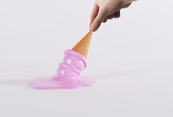 Hand holds melted ice in a waffle on the ground and light background. The concept of eating ice cream, cooling down.