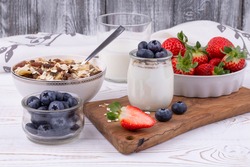 Healthy breakfast with homemade yoghurt and fresh strawberries and blueberries, muesli on a white wooden table in rustic style, close up, horizontal