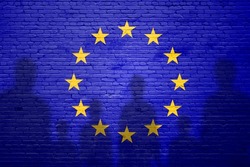 The refugees migrate to Europe union . Silhouette of illegal immigrants . Europe union migration policy. Europe Union flag painted on a brick wall