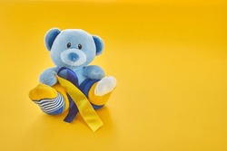 World Down Syndrome day background.Teddy bear with different socks on yellow background.