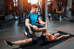 young woman exercising dead bug with personal trainer in gym